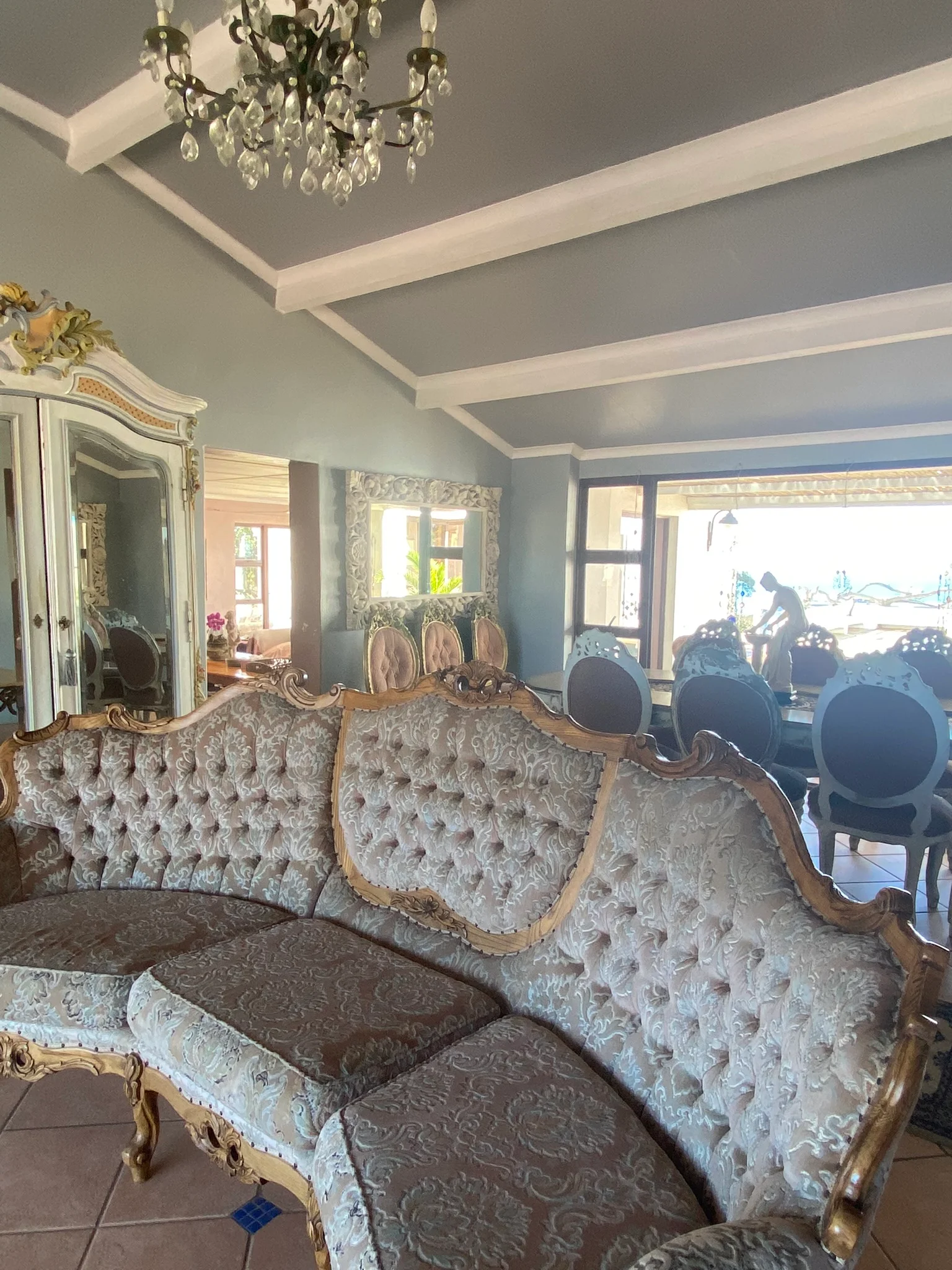 Manor entrance waiting area with vintage chandelier and tufted sofa